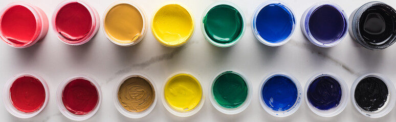 flat lay with multicolored bright gouache paints on marble white surface, panoramic shot