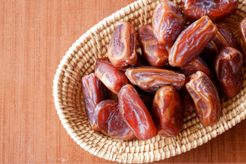 Date palm (Phoenix dactylifera L.) in the basket on a brown background.