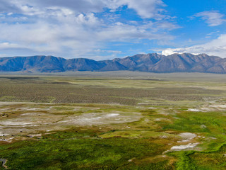 Aerial view of Long Valley next to Mammoth Lakes, Mono County, California. USA. Green grassland with mountain on the background during summer season. 