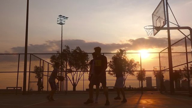 Sunset Basketball Game captures a group of young men playing basketball at sunset, creating a silhouette look.                                                                                          