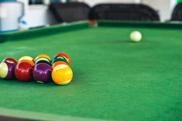 billiards balls triangle foreground on green game table surface, copy space 