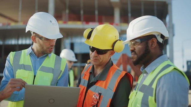 Diverse Team of Specialists Use Laptop Computer on Construction Site