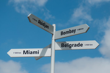 Closeup of destination panels with different cities for holidays on cloudy sky background