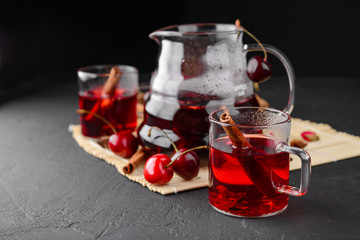 Freshly brewed tea with cherries on a dark concrete background