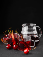 Freshly brewed tea with cherries on a dark concrete background