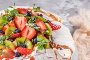 Vintage cake stand with Meringue dessert Pavlova with sugar powder, fresh strawberries, kiwi, blueberries and mint. Homemade baking