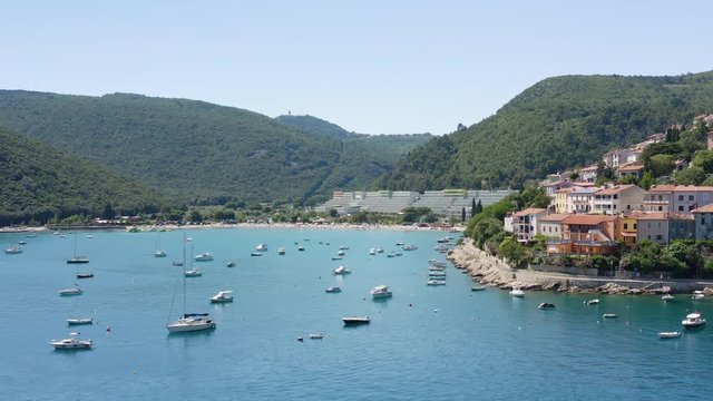 Panoramic Aerial view from the sea of Ship Boats Yacht moored in Rabac, Croatia . Amazing resort town on Kvarner Bay. Croatian Touristic destination with crystal clear blue water in Mediterranean.