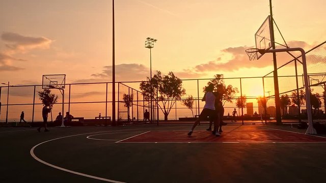 Sunset Basketball Game captures a group of young men playing basketball at sunset, creating a silhouette look.                                                                                          