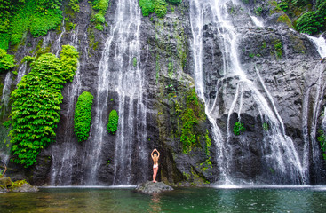 Girl in swimsuit on Waterfall background Banyumala with cascades among the green tropical trees and plants in the North of the island of Bali, Indonesia