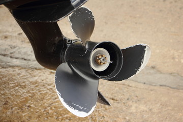 Used black outboard three-blade aluminum propeller with damaged edges, repair outboard motor props
