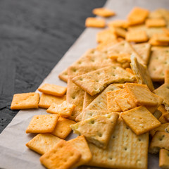 Salty square crackers on a paper and dark concrete background