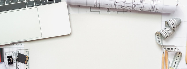 Architectural plans, pencil and ruler on the table. Laptop and accessories. Place for your text.