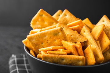 Black bowl with crackers on a dark concrete background