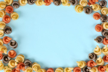 Frame of multicolored pasta in the form of curls. Close-up. Light background.
