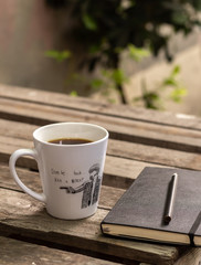White cup of coffee an a notebook on a wooden table