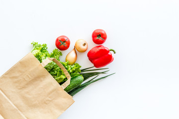 Healthy food with fresh vegetables in paper bag on white background top view