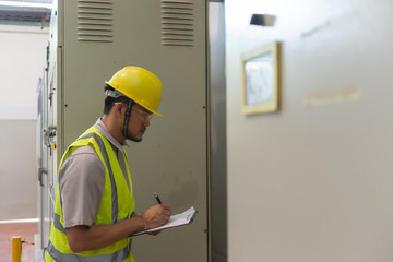 Asian electric engineer holding clipboard for checking and monitoring the electrical system in the control room,Technician thailand people working
