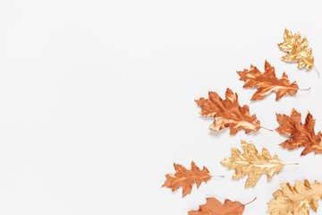 Autumn composition with a gold and copper spray painted natural leaves on white background. Flat lay, top view, copy space