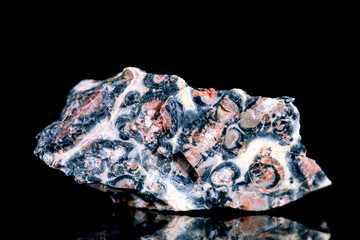 Rhodonit oder Pajsbergit Rohstein vor Hintergrund schwarz, Mineralien und Heilsteine