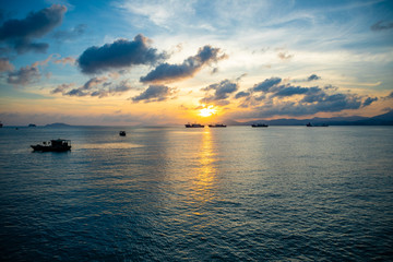 Fototapeta na wymiar Fishing boats on sea in sunset lights in Sanya, Hainan, China
