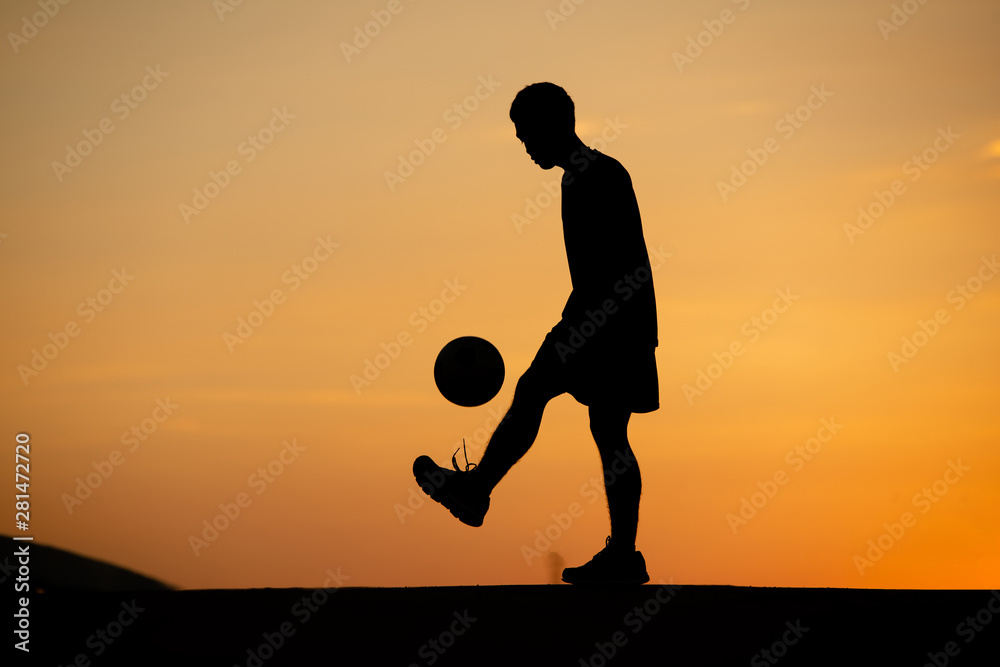 Canvas Prints Silhouette of a man playing soccer in golden hour, sunset.