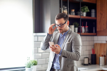 Man in the kitchen at the morning looking at the mobile phone