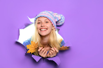 Happy girl in hat with maple leaves. Happy girl holds leaf. Autumn sales. Autumnal mood. Yellow maple leaf. Discount. Sales. Smiling woman with autumn leaves looking through paper hole. Copy space.