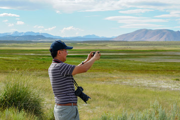 Asian man visiting and taking photo of the Wild Willy's Hot Spring in Long Valley, Mammoth Lakes, Mono County, California. USA. Natural hot springs from old volcanic activity.