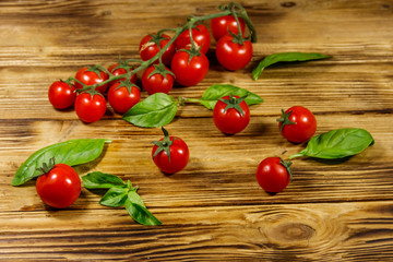 Fresh cherry tomatoes with green basil leaves on a wooden table