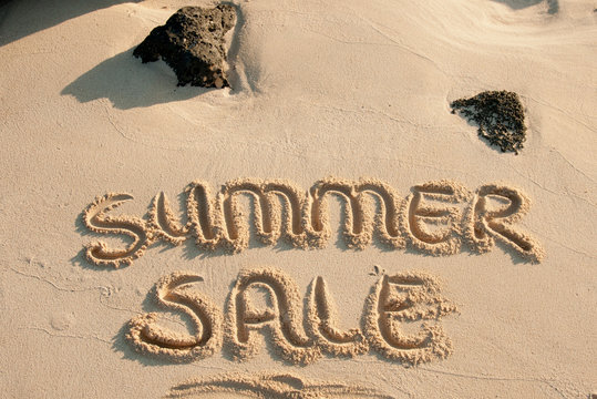 summer sale written in the sand on a beach