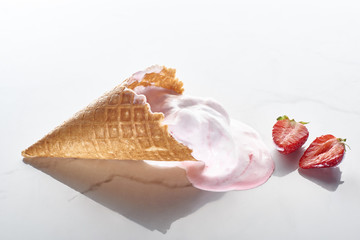 delicious ice cream in waffle cone near strawberries on marble grey background
