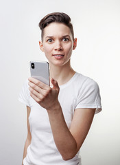 Happy funny millennial woman's celebrating win or victory, triumph, holding a phone. Cheerful excited girl, laughing, having fun, using cell phone apps. Isolated on white studio blank background.