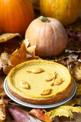 Traditional American pumpkin homemade cake, decorated with cookies on a background of pumpkins and autumn leaves.