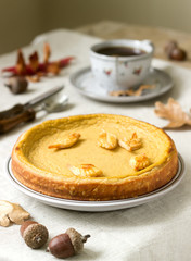 Traditional American pumpkin homemade cake, decorated with cookies on a background of pumpkins and autumn leaves.