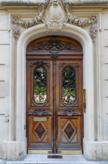 Baroque architecture of arch door entrance of antique building in Paris France. Vintage wooden doorway with ornate gratings and whimsical stone fretwork arch of ancient house with sculptural details.