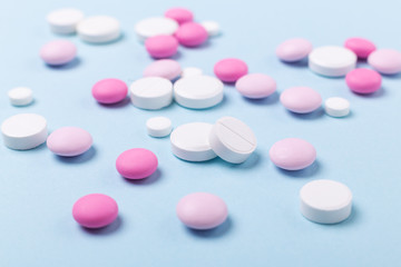 Pink and white tablets on blue background Heap of assorted various medicine tablets Health care Close-up Copy space