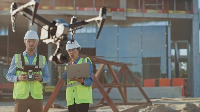 Two Specialists Use Drone on Construction Site. Architectural Engineer and Safety Engineering Inspector Fly Drone on Building Construction Site Controlling Quality. Focus on Drone