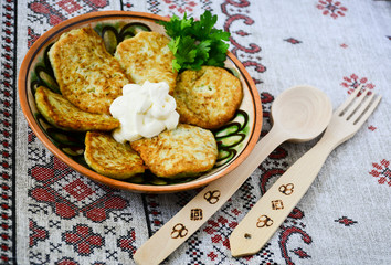 Traditional Slavic cuisine potato pancakes. Potato pancakes. Food served on a clay plate with sour cream. In ancient times, a wooden spoon and a wooden fork were sold. The towel is decorated with a na