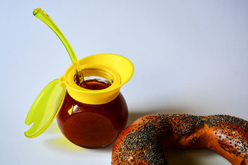 Fresh donated crispy bagel with poppy seeds on a white plate with tasty natural apricot jam and a...