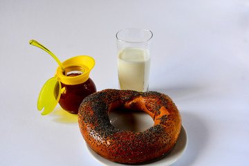 Fresh donated crispy bagel with poppy seeds on a white plate with tasty natural apricot jam and a...