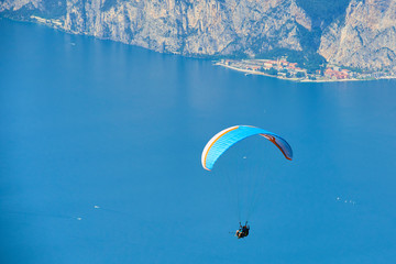 Paraglider flying over the Garda Lake (Lago di Garda or Lago Benaco), Panorama of the gorgeous Garda lake surrounded by mountains. Paragliding is very popular sport in Monte Baldo. Malcesine, Italy