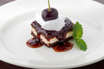 waffle cake with cherry and whipped cream with mint leaf on white plate