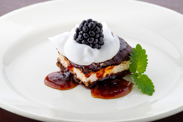 waffle cake with blackberry and whipped cream with mint leaf on white plate