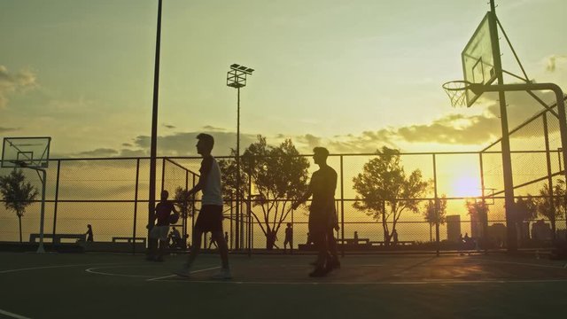 Sunset Basketball Game This stock footage captures a group of young men playing basketball at sunset, creating a silhouette look.