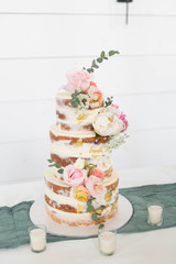 Naked Wedding Cake Decorated with Gold Foil and Flowers, Three Tiered Cake, White Background, Copy Space