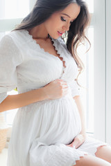 Young beautiful pregnant woman in white dress