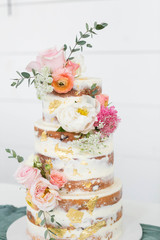 Naked Wedding Cake Decorated with Gold Foil and Flowers, Three Tiered Cake, White Background, Copy Space