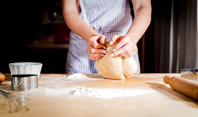 Fototapeta premium Making dough by female hands on wooden table
