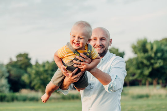 Caucasian father hugging playing with toddler baby boy. Parent holding carrying lifting child son on arms. Authentic lifestyle tender moment. Single dad family life concept. Happy fatherhood.