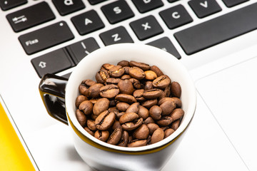 cup with coffee beans and laptop